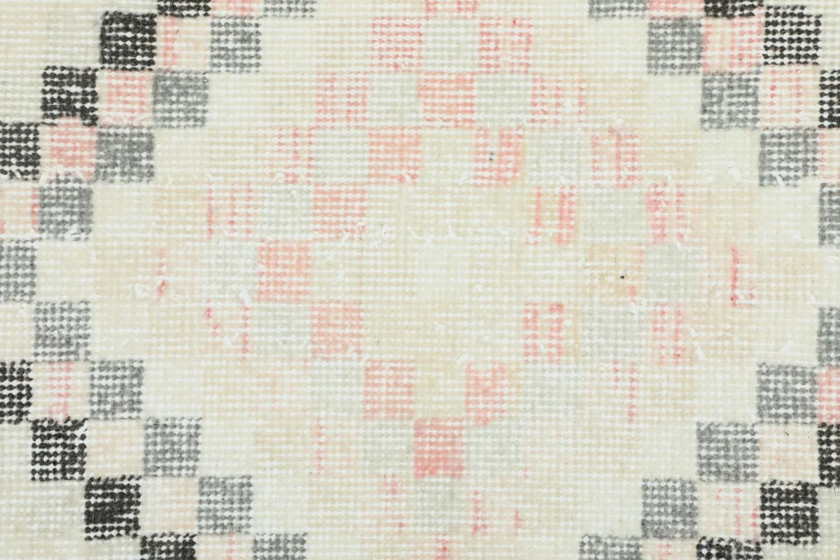 Extreme close-up of the wool pile and cotton foundation, revealing the hand-knotted construction and color variations.