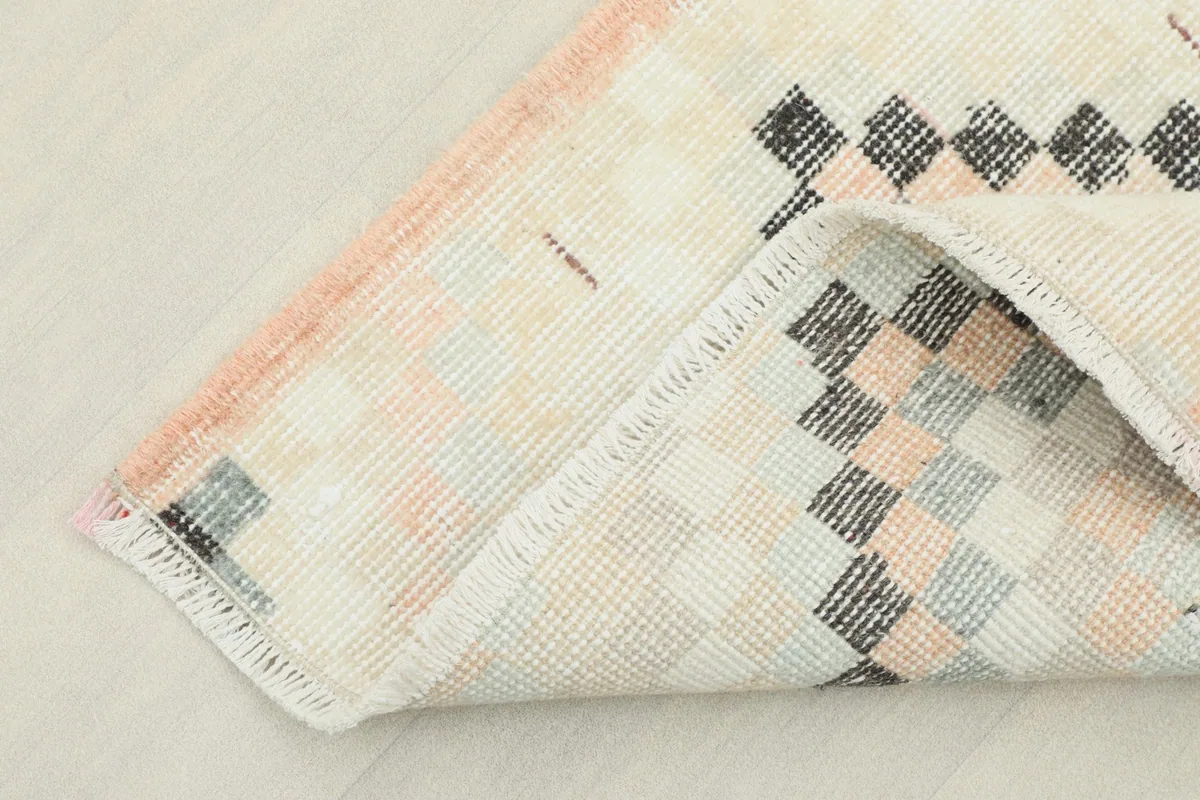 Corner of the rug folded to show the backside (foundation) and the neat, hand-finished edges.