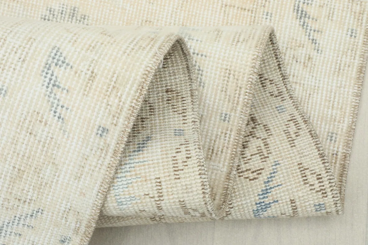 Close-up of the folded rug edge, revealing the wool pile and cotton foundation structure.