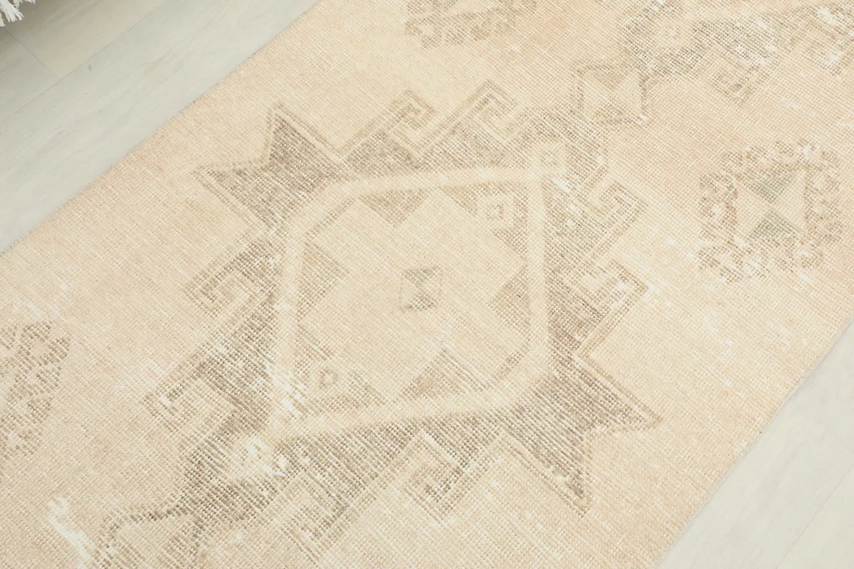Overhead close-up of a central geometric medallion motif on the ivory runner