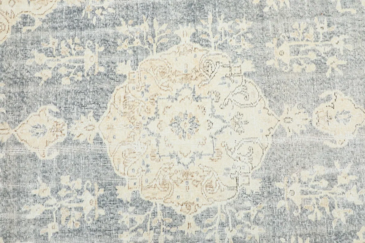 Detailed view of the central ivory medallion and surrounding gray field with faded patterns.