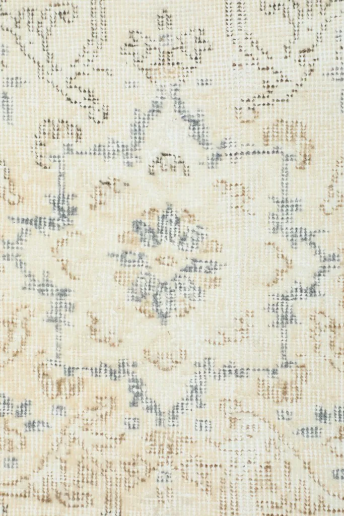 Close-up of a section of the rug, showing the wool pile and intricate geometric motifs in ivory and beige.