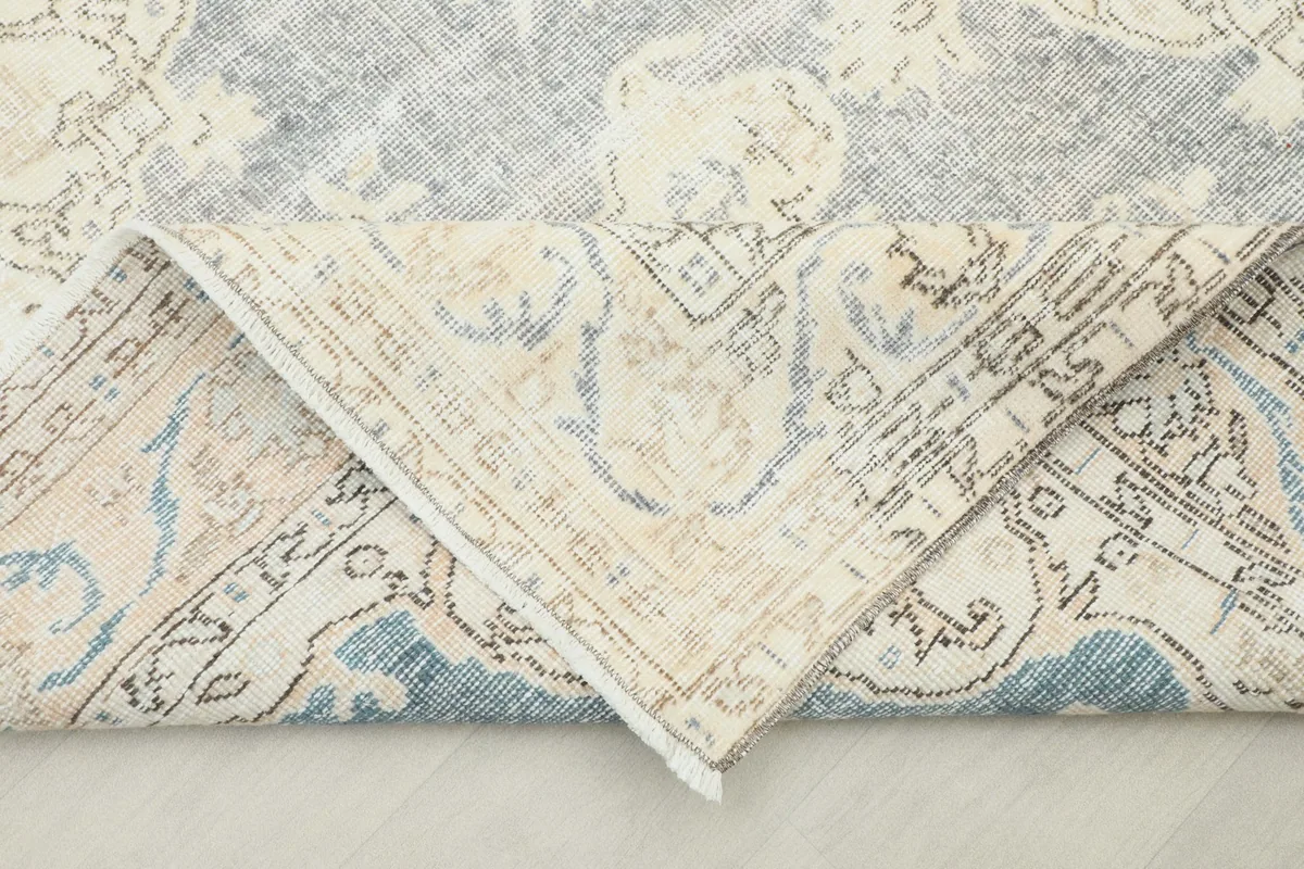 Folded corner of the rug revealing the cotton foundation and reverse side of the hand-knotted construction.