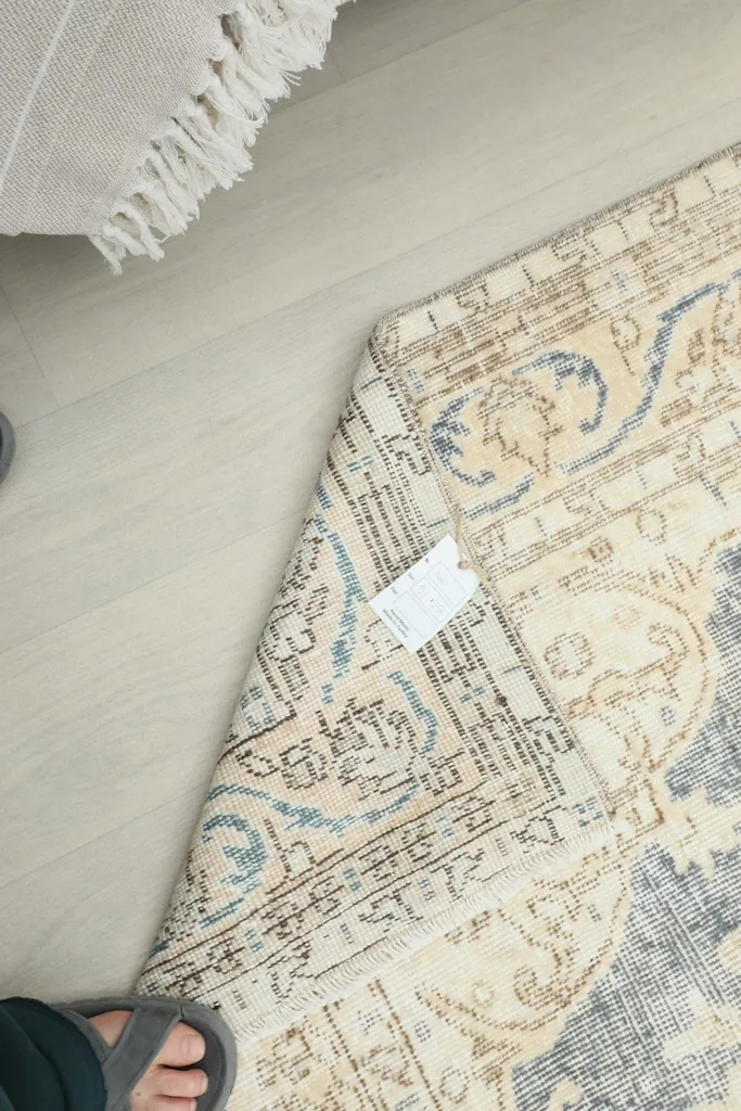 Overhead view of a folded corner with a tag, illustrating the rug's thickness and texture.