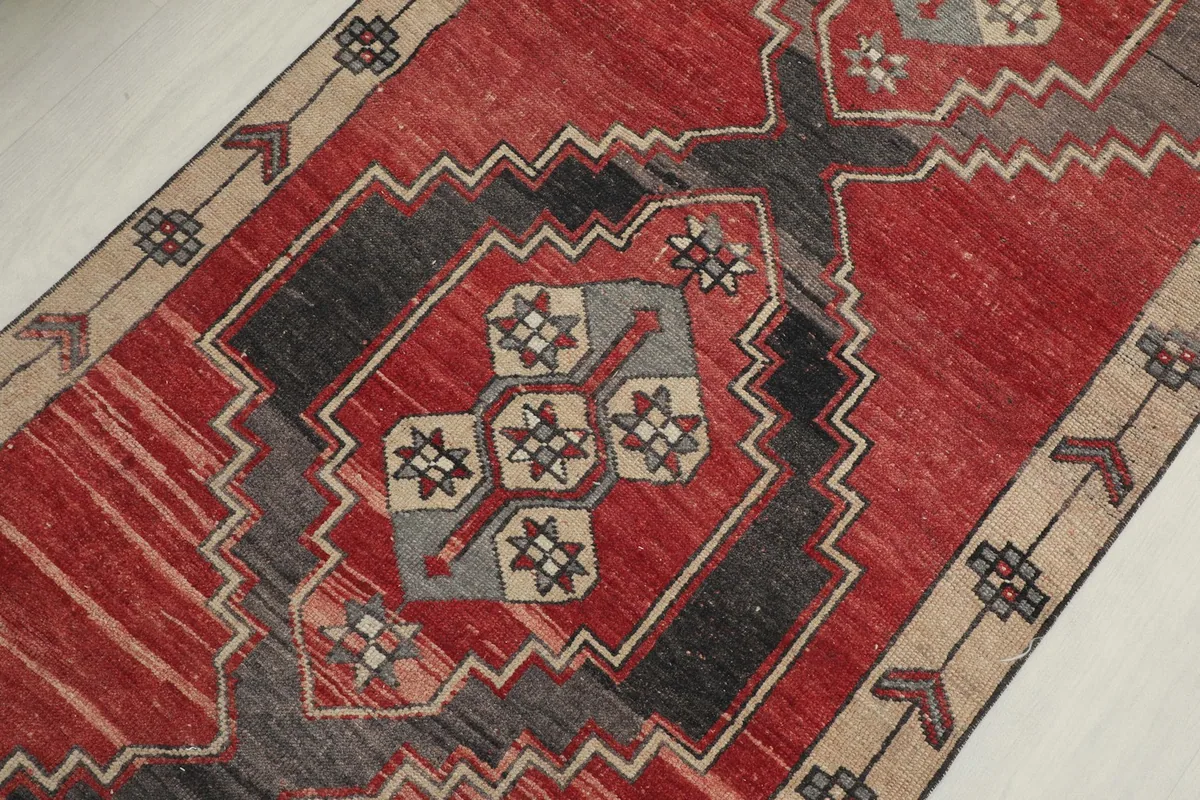 Detailed shot of the central geometric motif in charcoal, gray, and beige on the red background