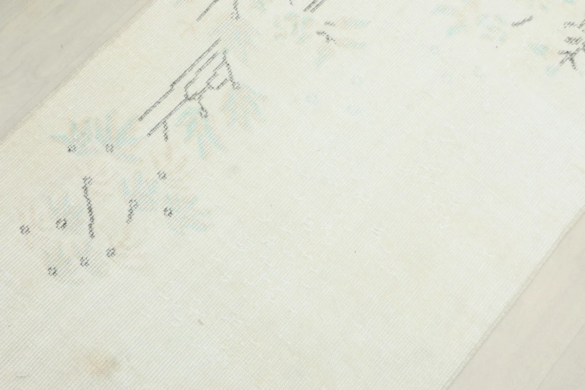 Detailed view of the rug's faded geometric motifs and texture from an angle