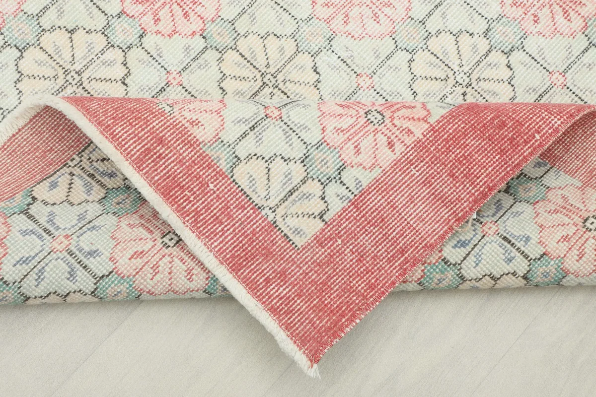 Folded corner revealing the back of the hand-knotted wool rug, showing the cotton foundation.
