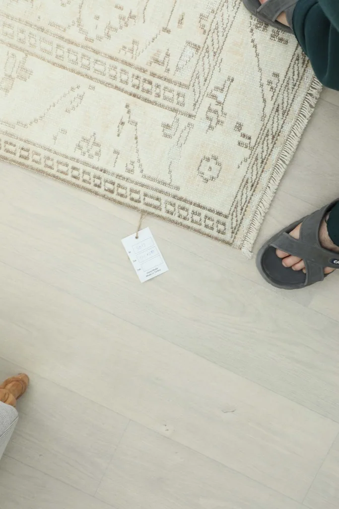 Overhead view of the rug's corner with a tag and feet for scale, showing part of the border.