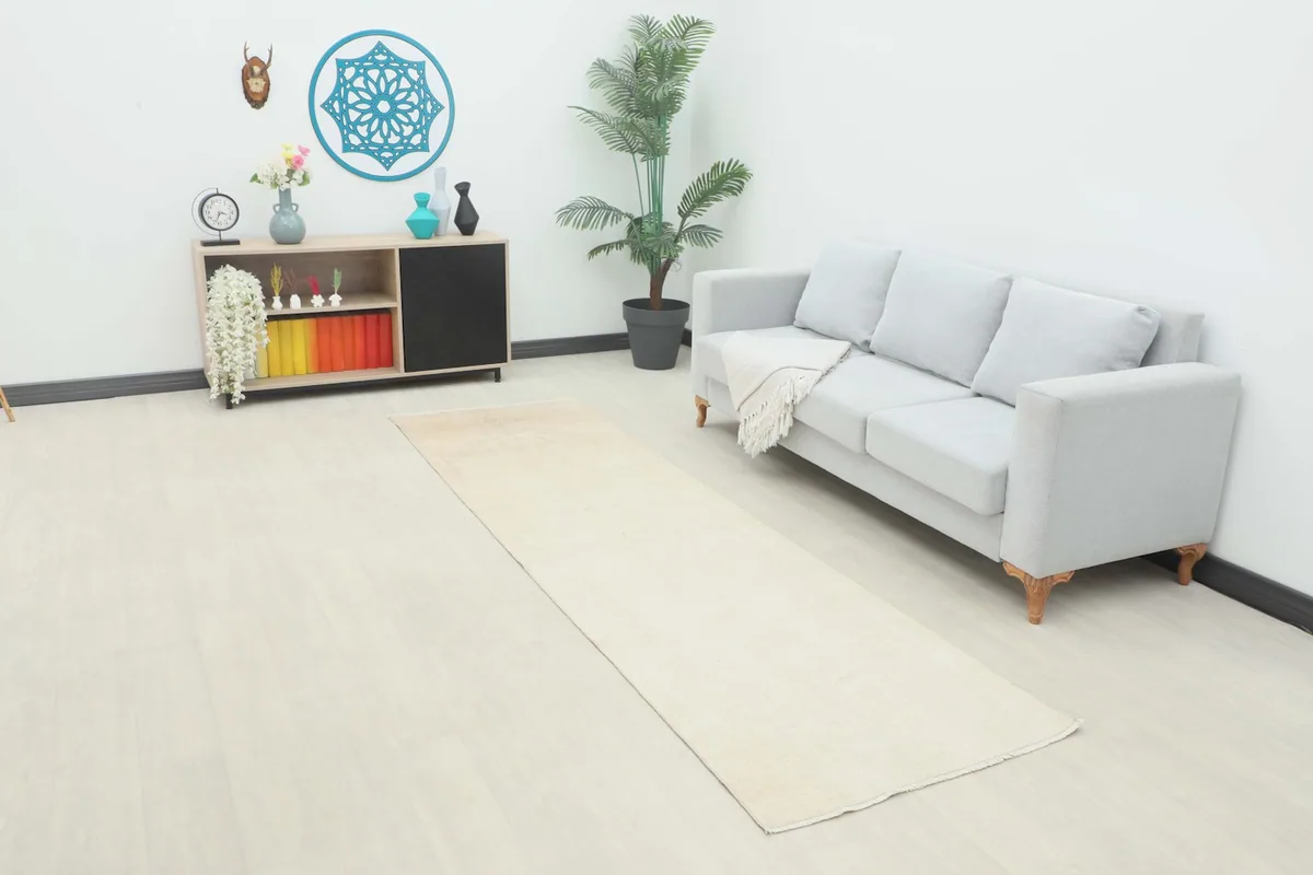 Vintage ivory and beige runner rug in a room setting with a light gray sofa and modern decor