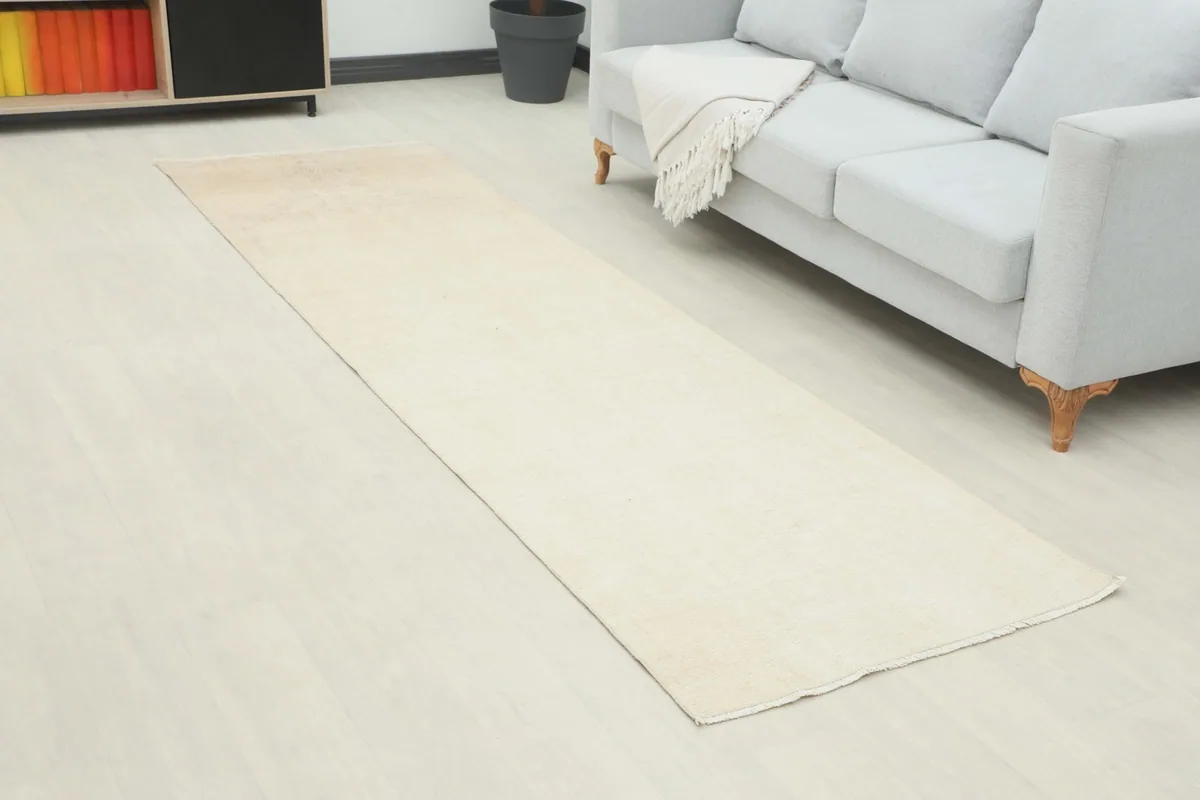 Angle view of the ivory and beige runner rug extending into a living space with a sofa