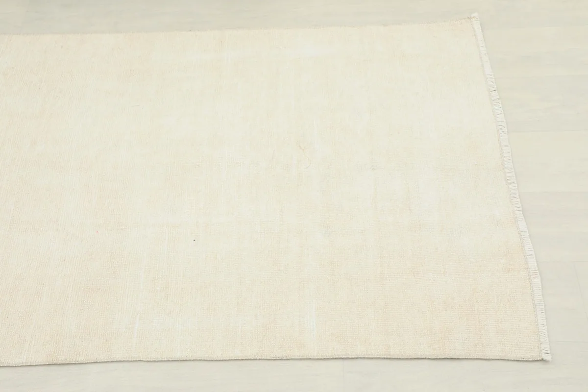 Close overhead view of the end of the ivory and beige runner rug, showing subtle texture