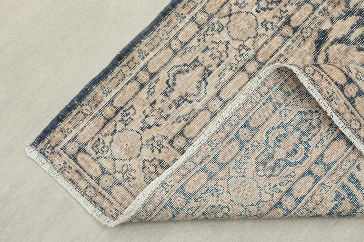Rug corner folded back, revealing the cotton foundation and the reverse side of the pattern