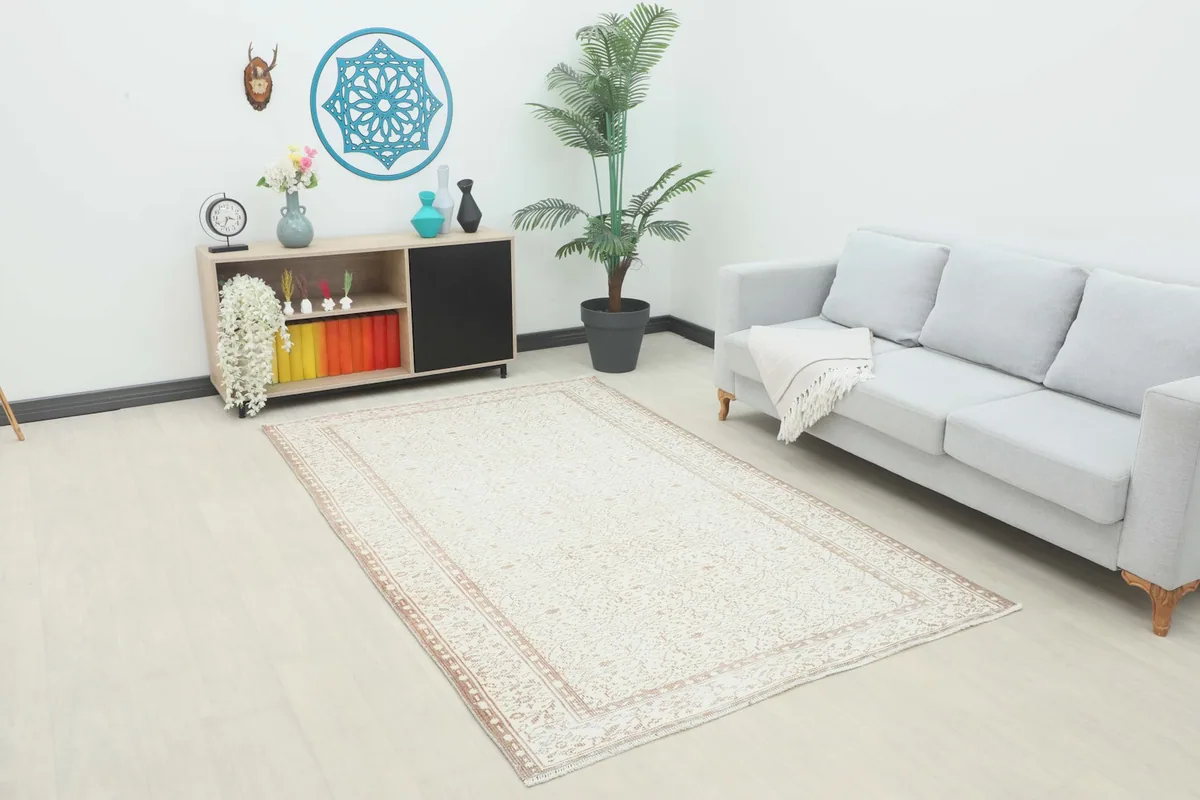 Vintage cream rug displayed in a bright living room setting with a gray sofa