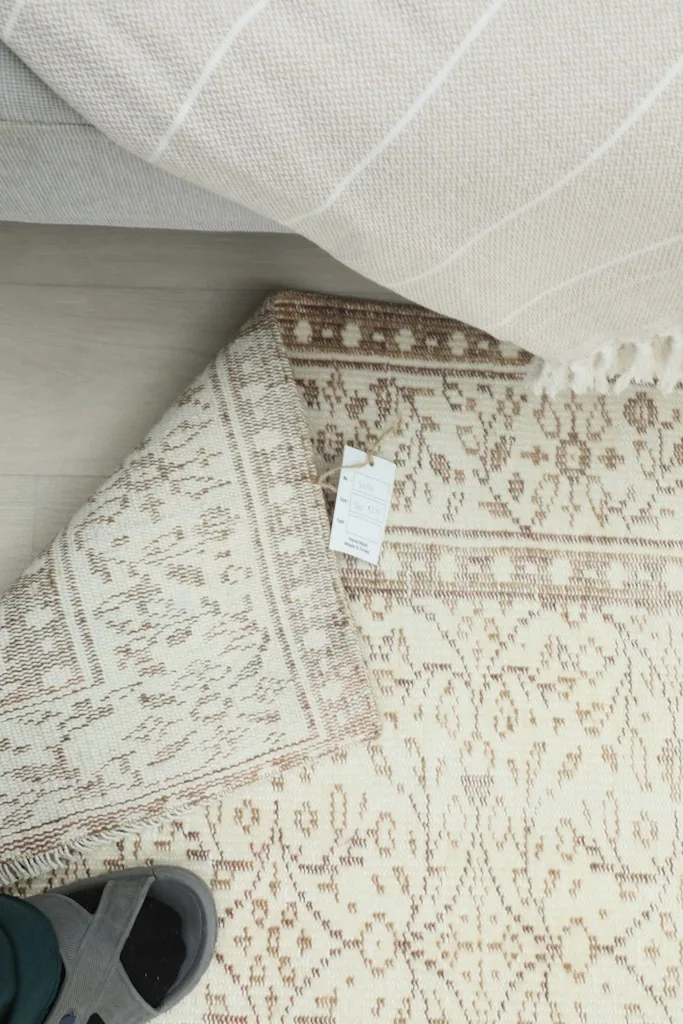 Overhead view of the rug's back and pile, with a tag indicating its material and origin