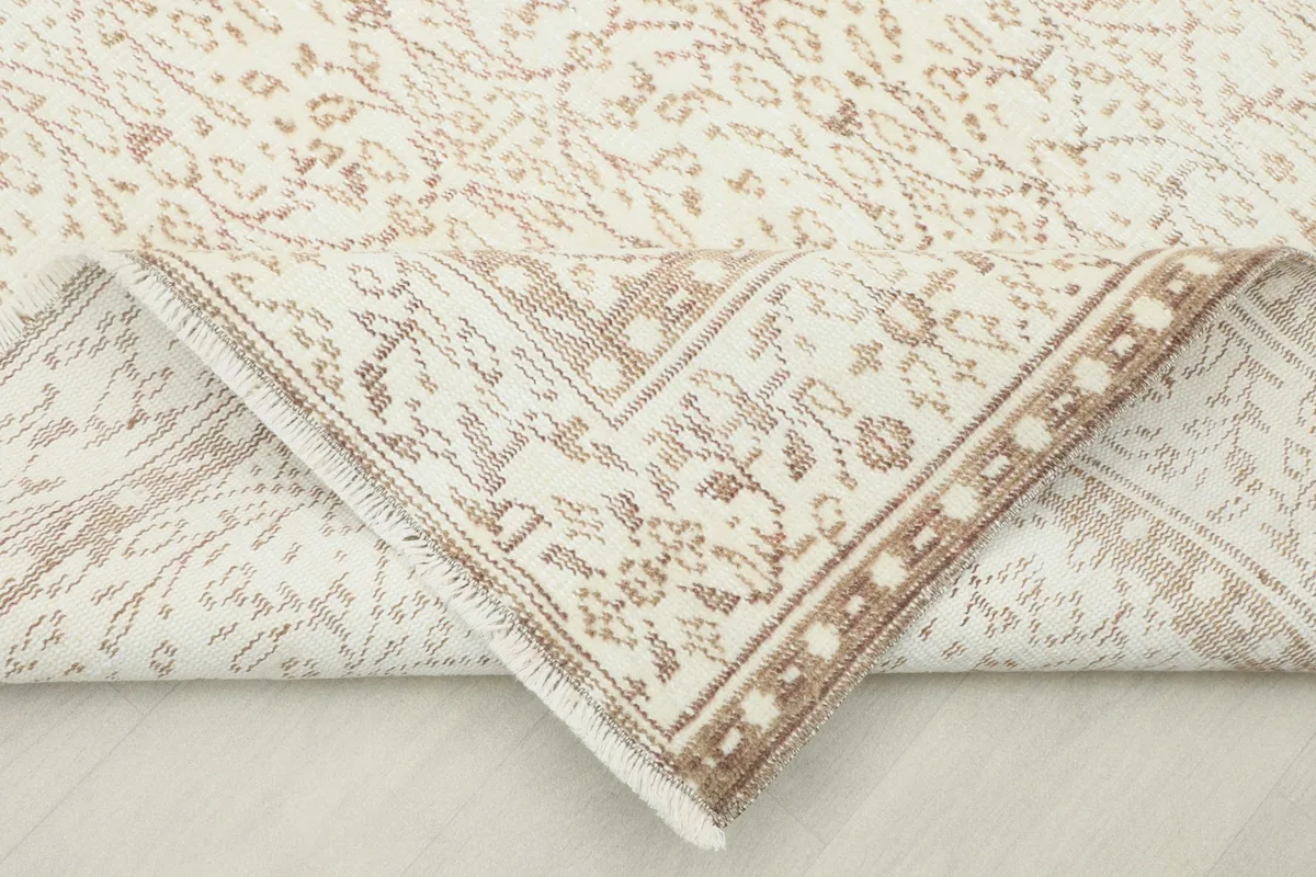 Corner of the rug folded back to show the hand-knotted construction and back of the pile