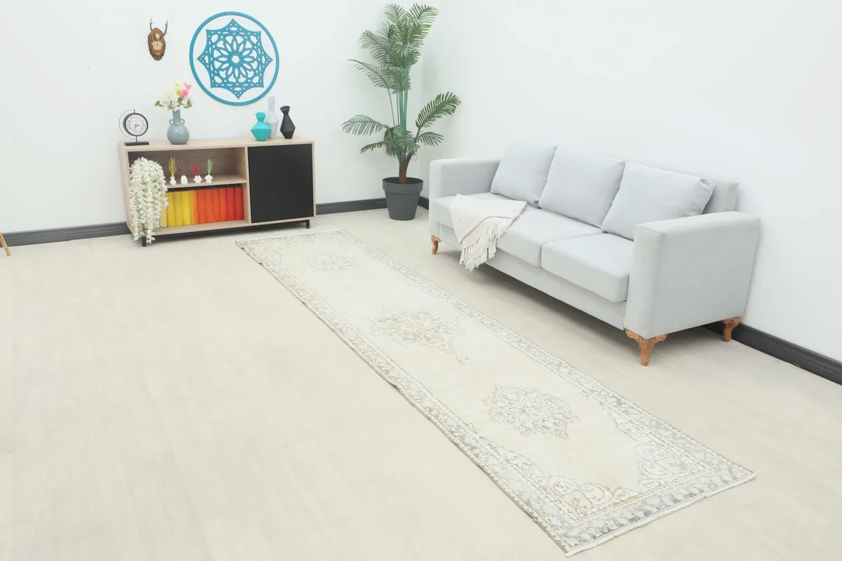 Vintage runner rug displayed in a living room setting next to a gray sofa and wooden cabinet