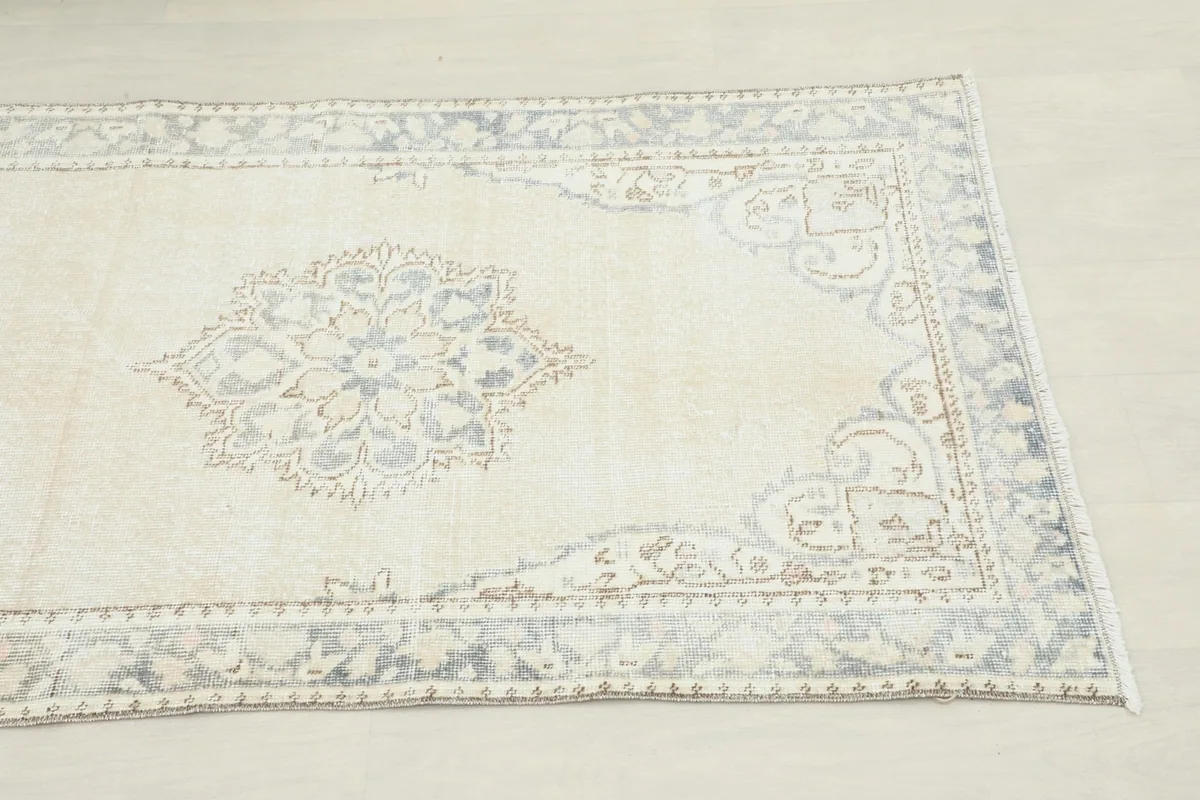 Close-up of one end of the runner rug, highlighting the ivory field and gray medallion motif