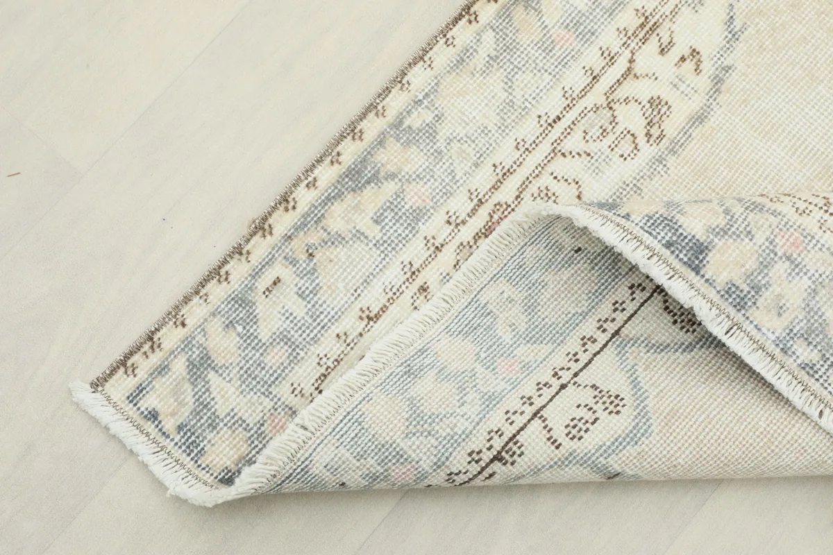 Corner of the rug folded back, revealing the hand-knotted wool pile and cotton foundation