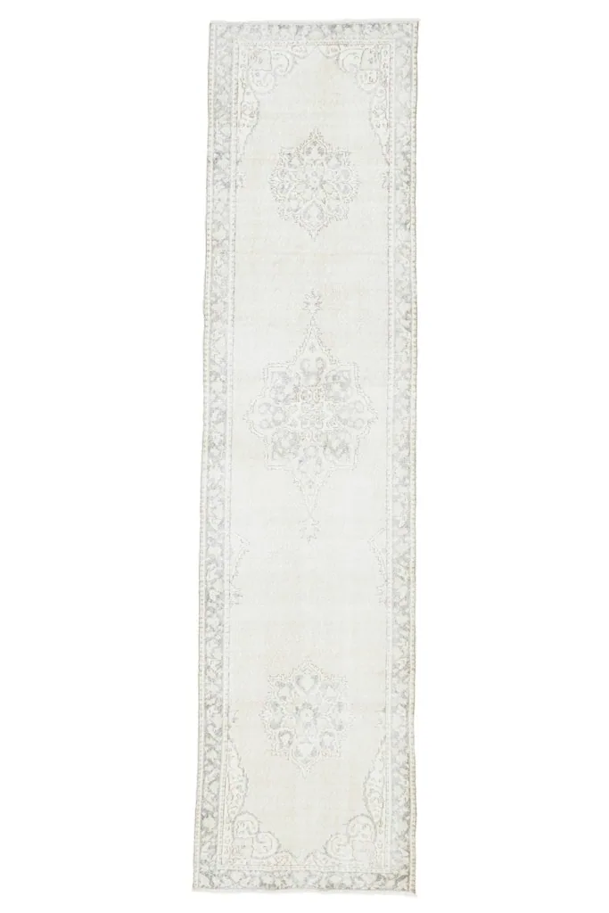 Full overhead view of the vintage ivory and gray Anatolian runner rug on a white background