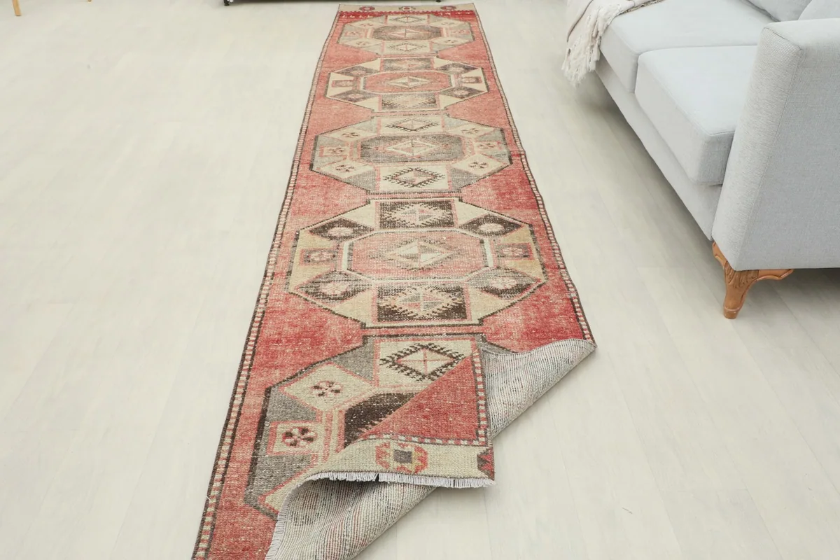 Runner rug laid out in a room, with one end slightly folded to reveal the underside