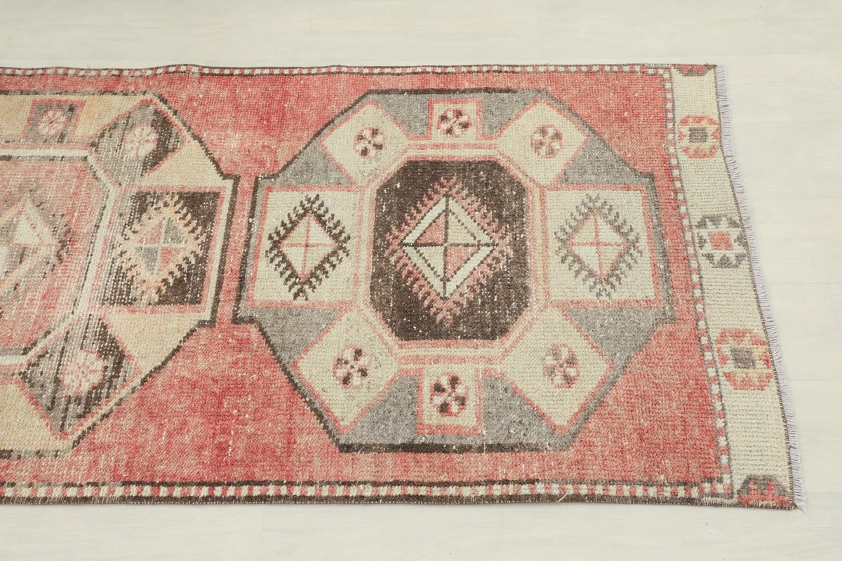 Close-up of a central geometric medallion showing rose, gray, and brown colors and wool texture