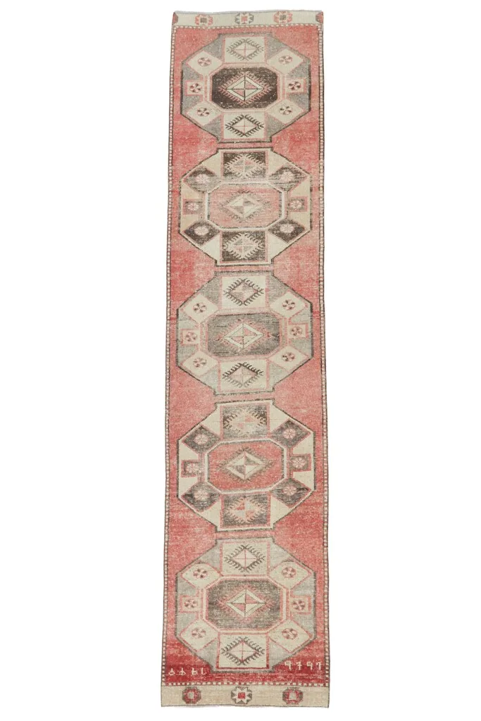 Full overhead view of the vintage rose and gray geometric Anatolian runner on a white background