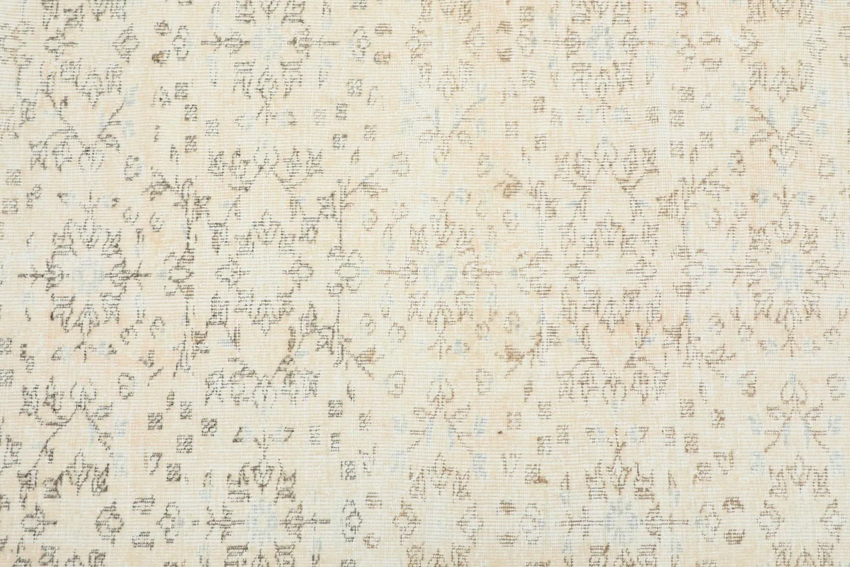 Close-up view of the rug's ivory field with subtle tan and blue geometric motifs