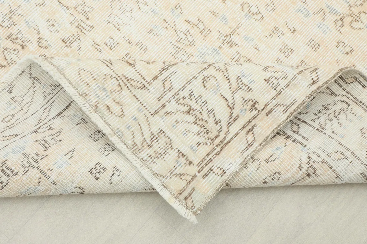 Corner of the rug folded back to show the low pile and original backing