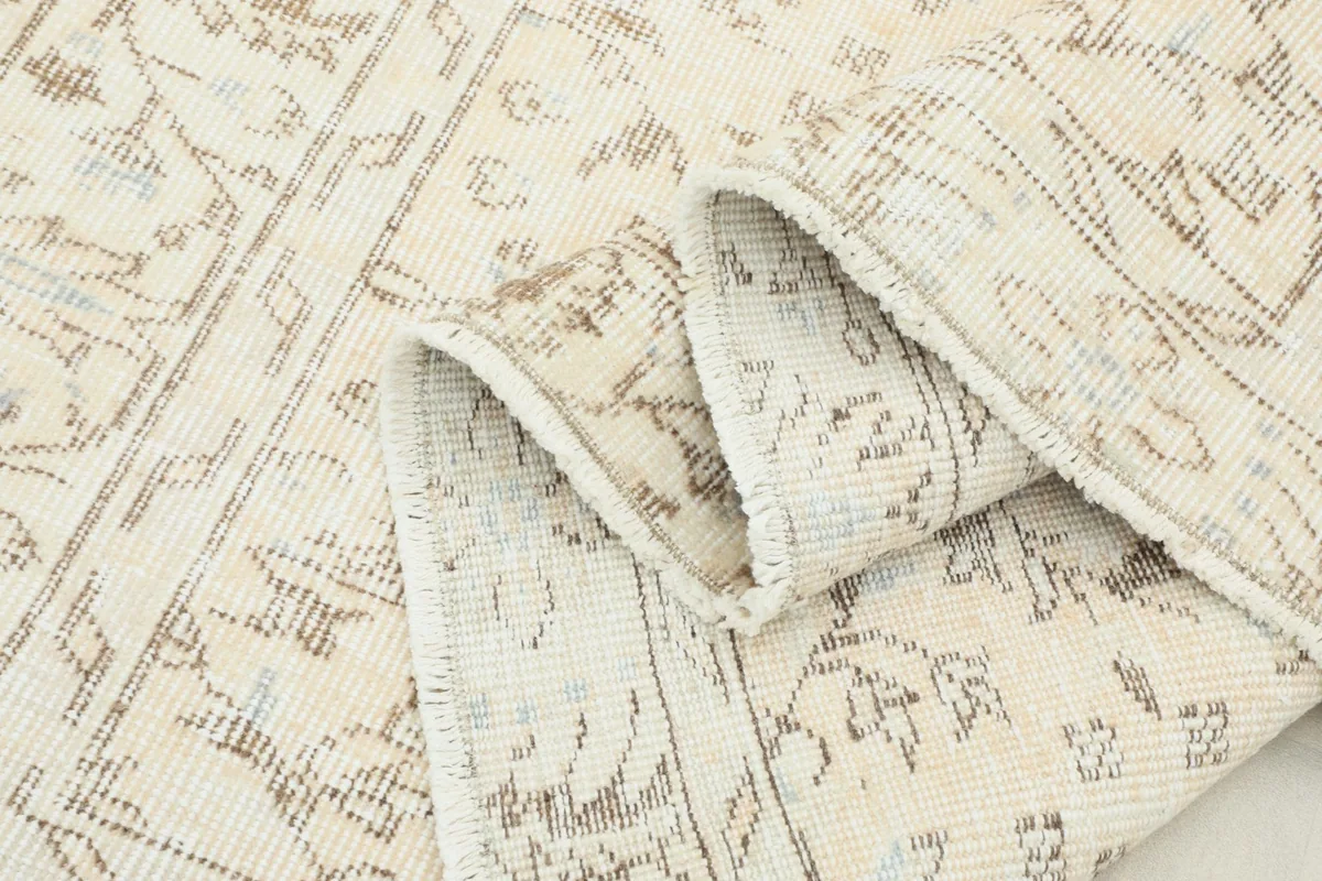 Rolled section of the rug showing the low pile texture and hand-knotted construction