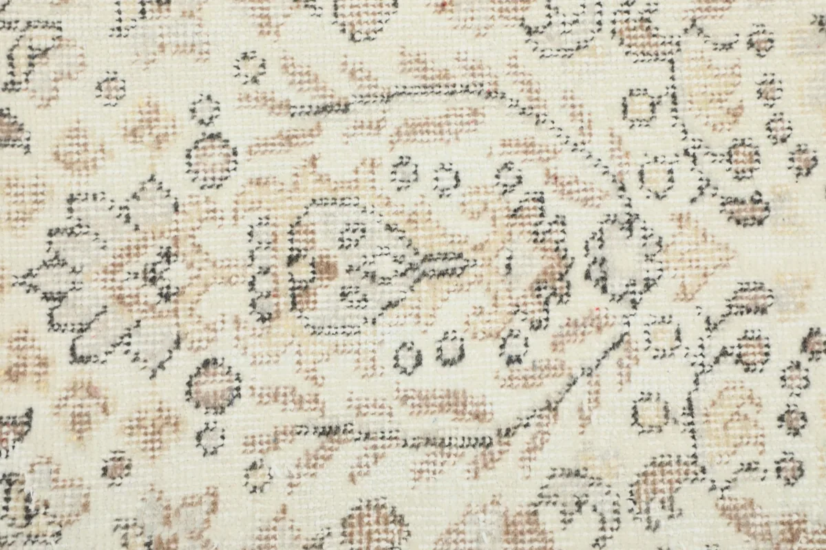 Detailed view of the hand-knotted wool pile showing the subtle tan and gray floral motifs
