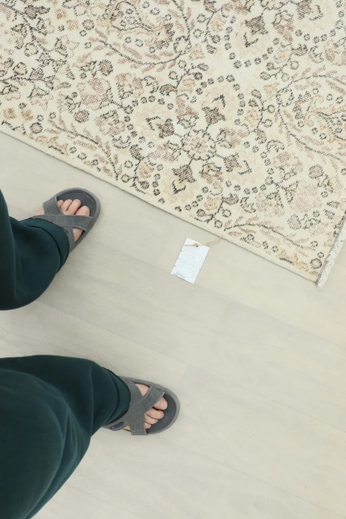 Overhead shot of feet in sandals next to a corner of the rug, showing scale