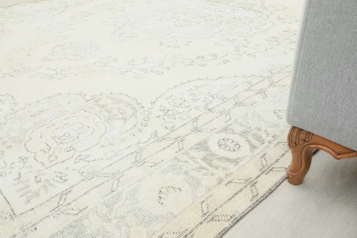 Partial view of the rug extending into a room, next to a piece of furniture