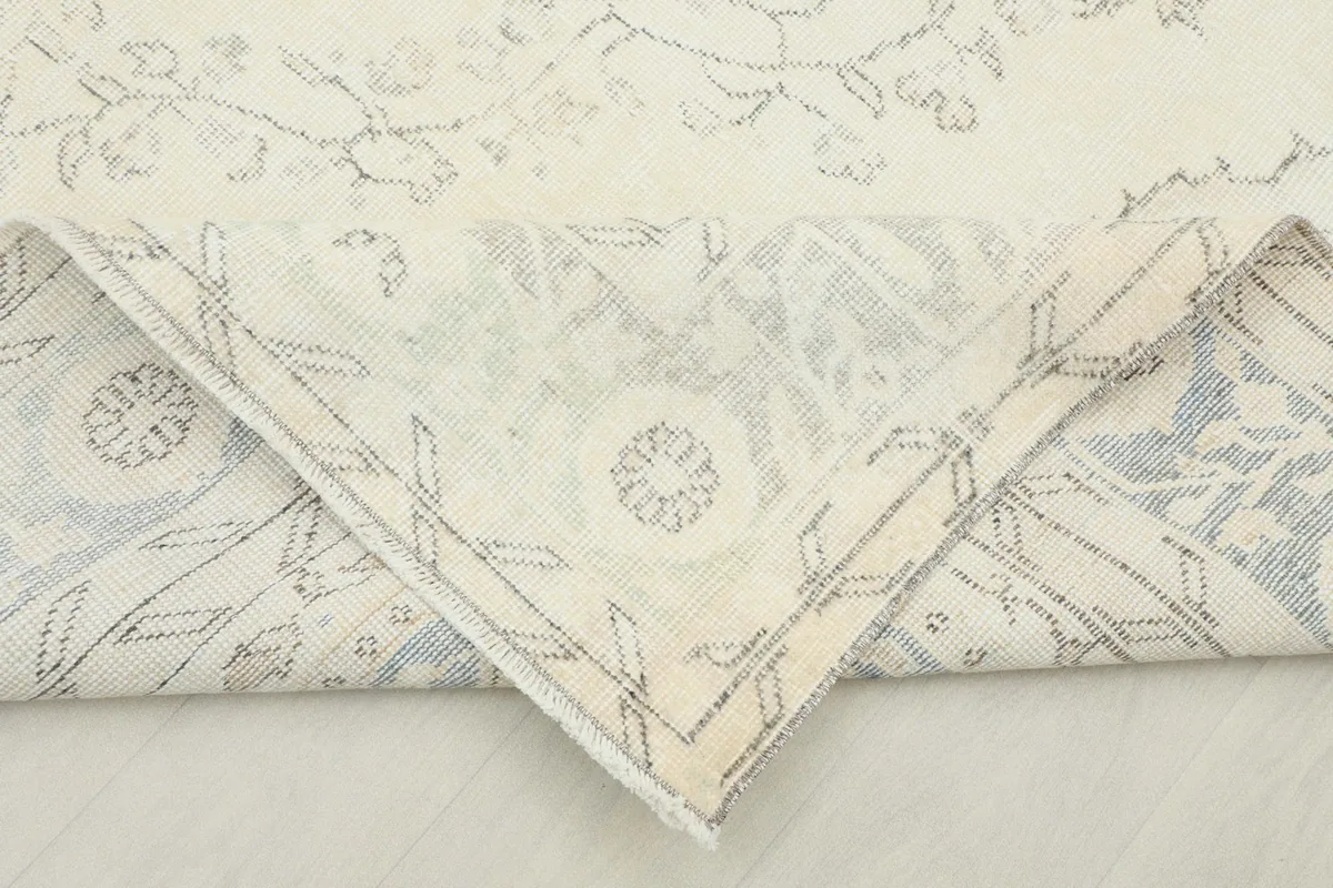 Corner of the rug folded back to reveal the hand-knotted cotton foundation