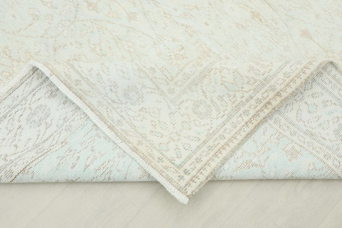 Corner of the rug folded back to reveal the cotton foundation and hand-knotted construction.