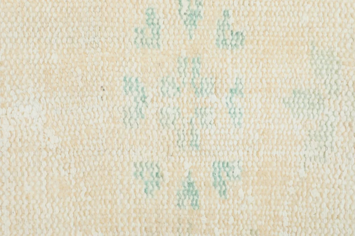Close-up showing the texture of the low wool pile and the faded blue tribal motifs.
