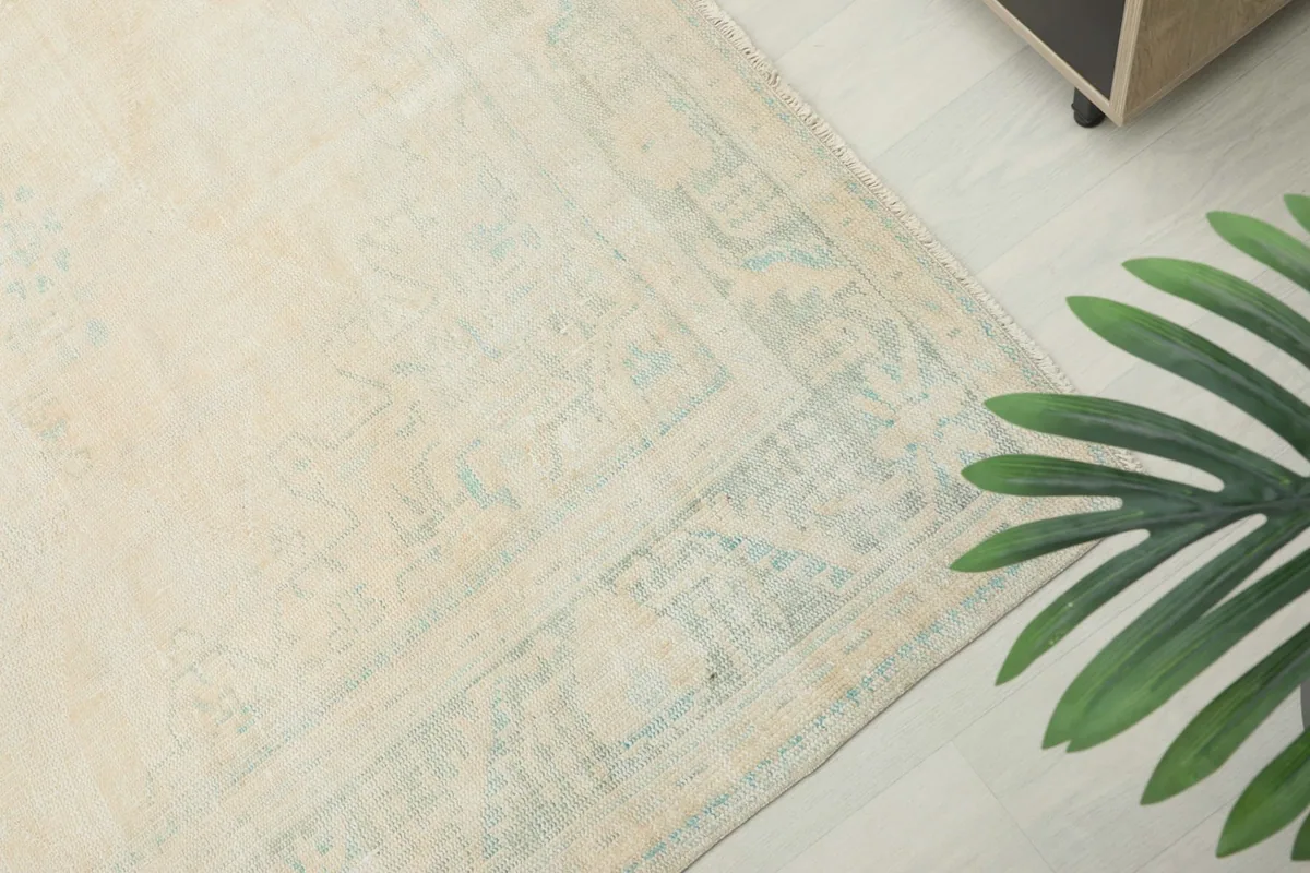 Detailed view of the faded blue border design and corner of the ivory area rug.