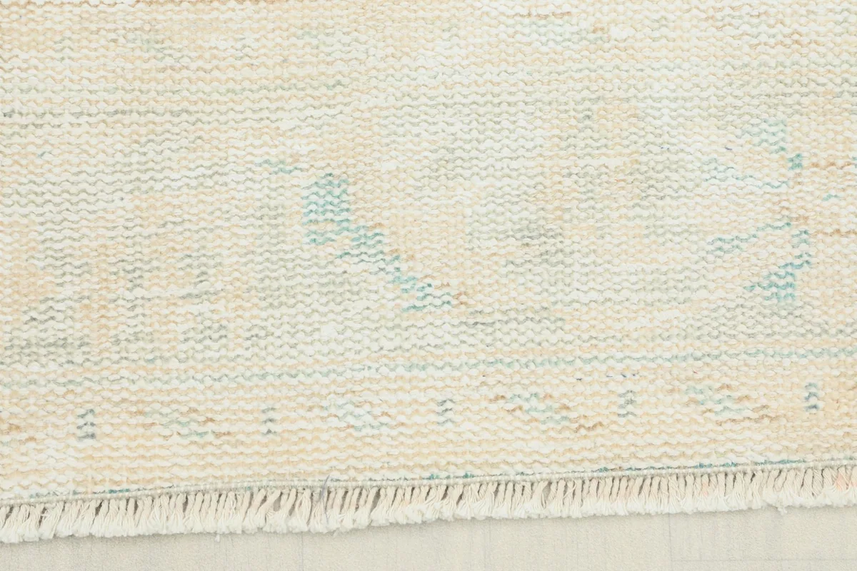 Close-up view of the short, clean fringes and edge of the hand-knotted wool rug.