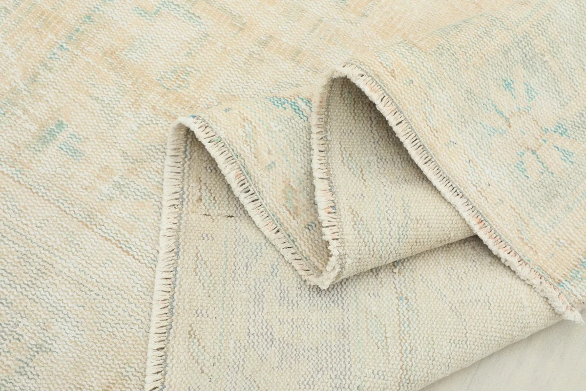 Folded edge of the rug, highlighting its thickness and wool pile on cotton foundation.