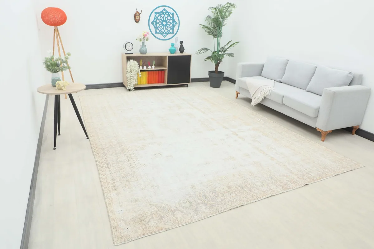 Angle view of the large vintage ivory beige rug laid out in a modern room setting with a sofa.