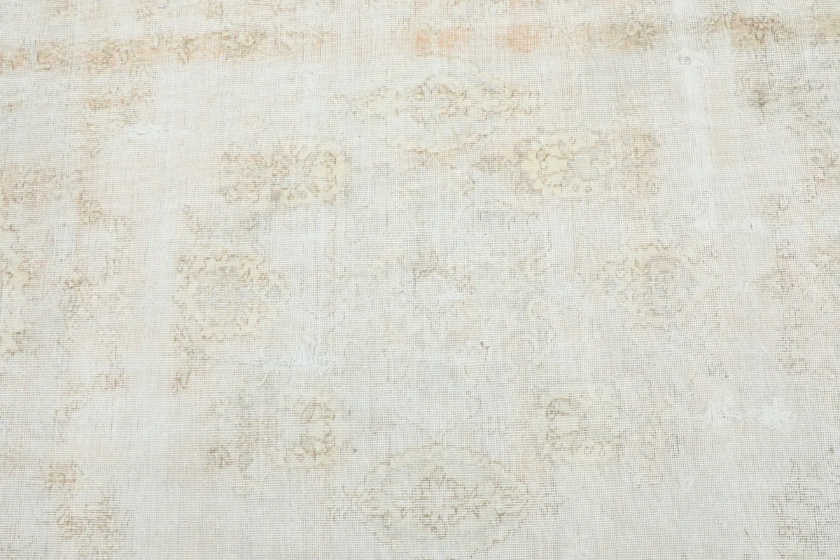 Close-up of the faded ivory and beige field, showing subtle floral and geometric patterns.