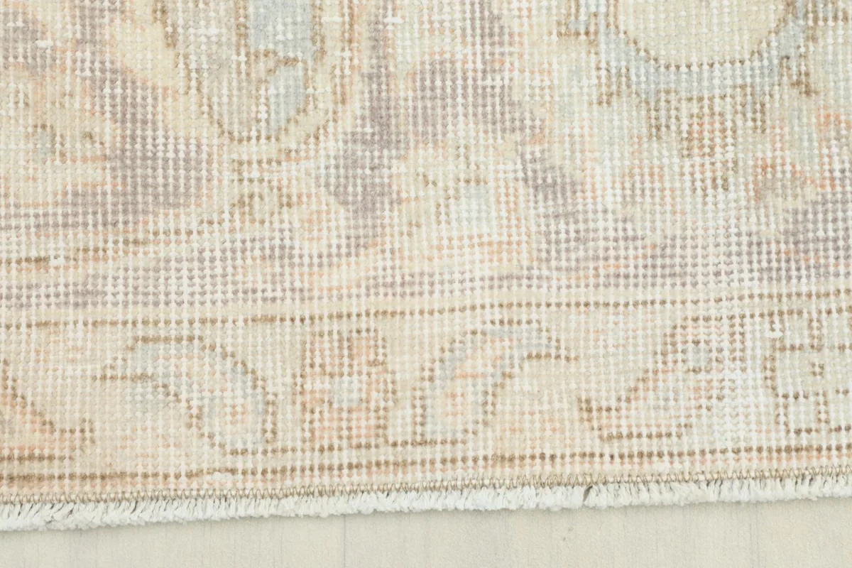 Detailed view of the rug's border pattern in light beige and tan tones.
