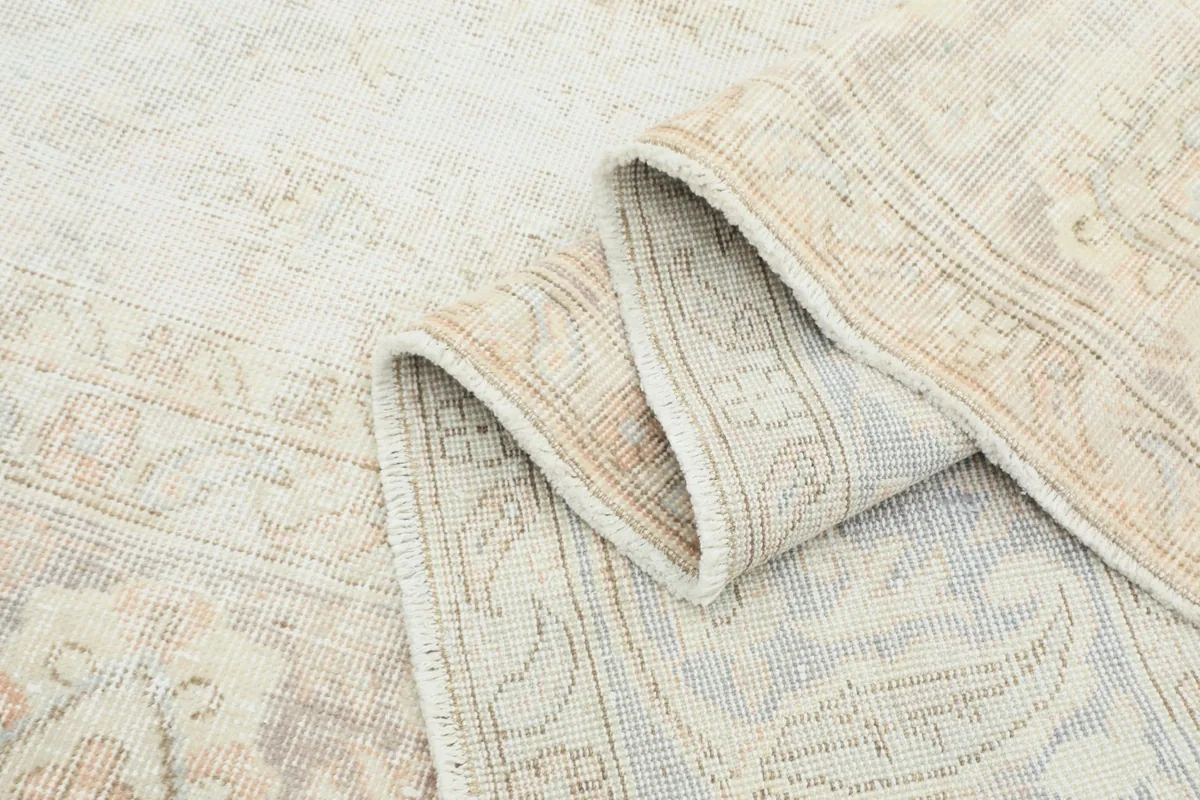 Rolled edge of the rug showing the low wool pile and the hand-knotted construction.