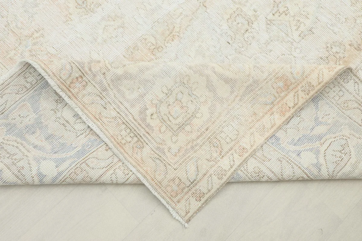 Corner of the hand-knotted rug folded to show the cotton foundation and reverse side.