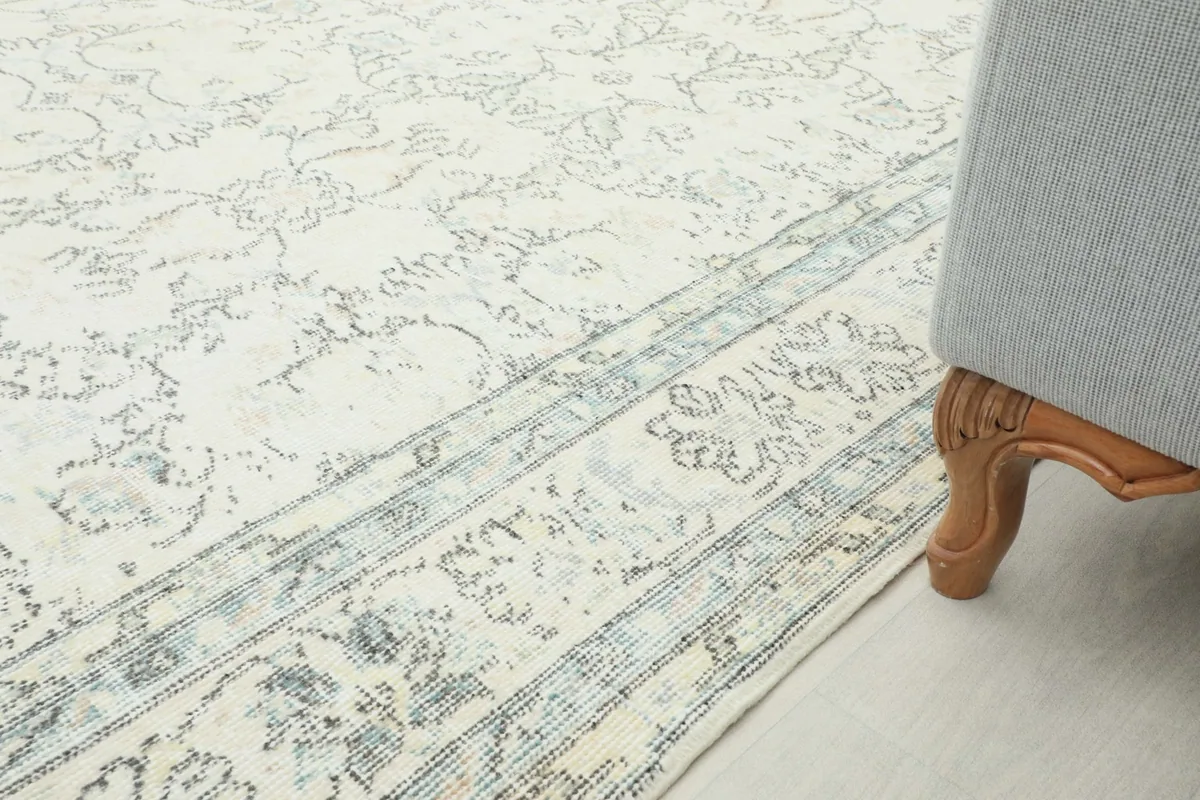 View of the rug's edge and border design next to a sofa leg