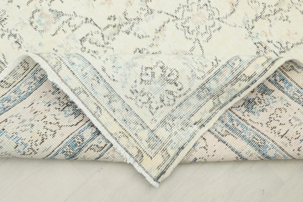 Corner of the rug folded back, revealing the wool pile and cotton foundation