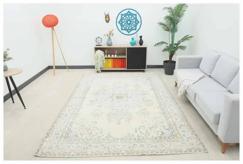Full top view of the 6'7" x 9'8" cream and blue vintage Anatolian rug on a white floor in a room setting.