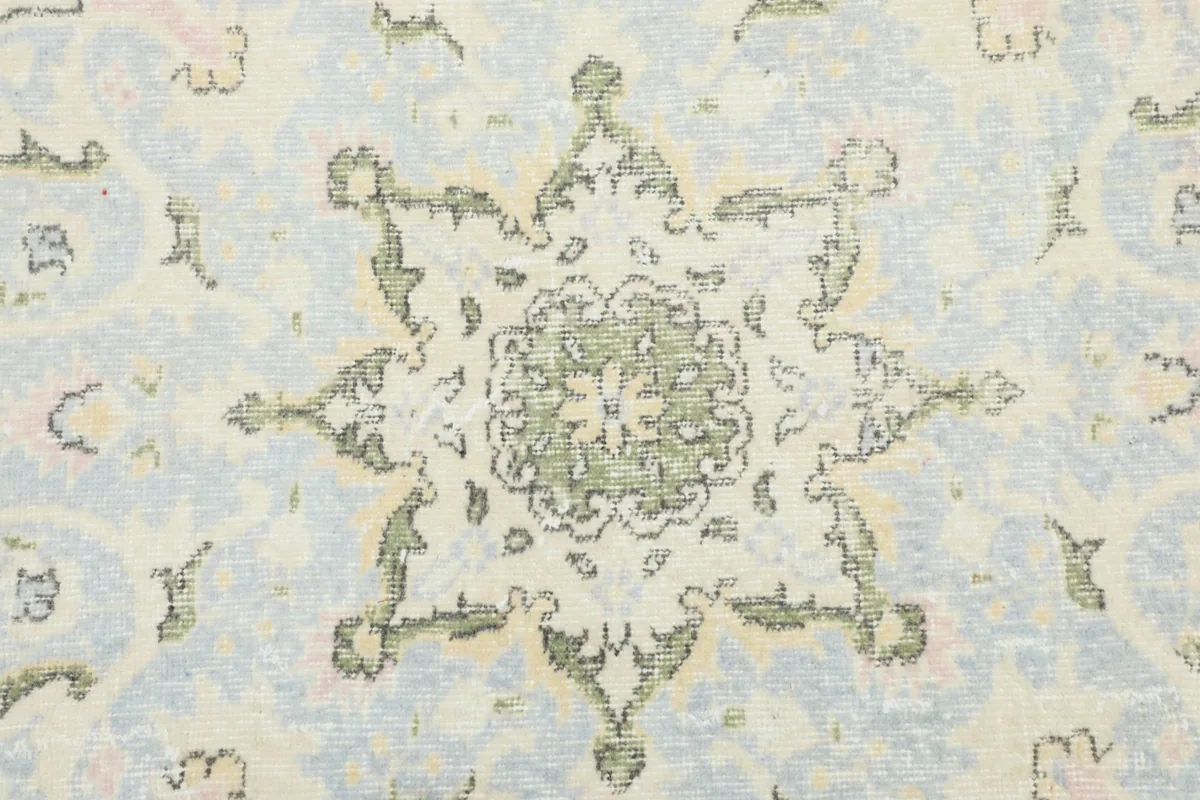 Detailed view of the intricate green and blue patterns within the central medallion of the rug.