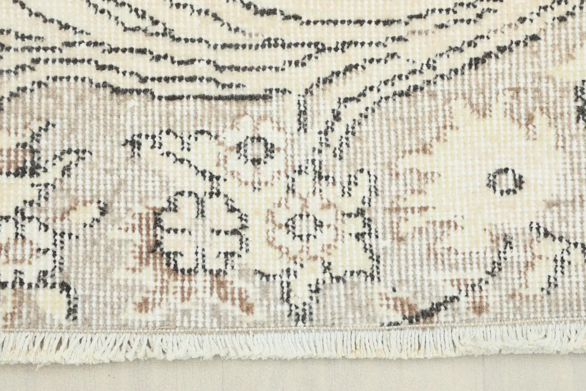 Close-up of the rug's border showing beige, gray, and brown floral patterns and fringe