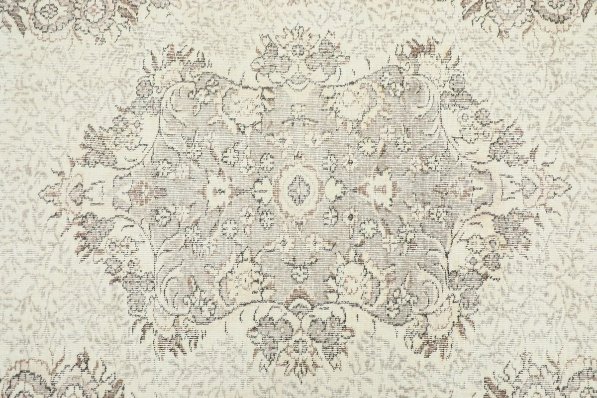 Overhead view focusing on the central medallion and surrounding floral motifs in beige and gray