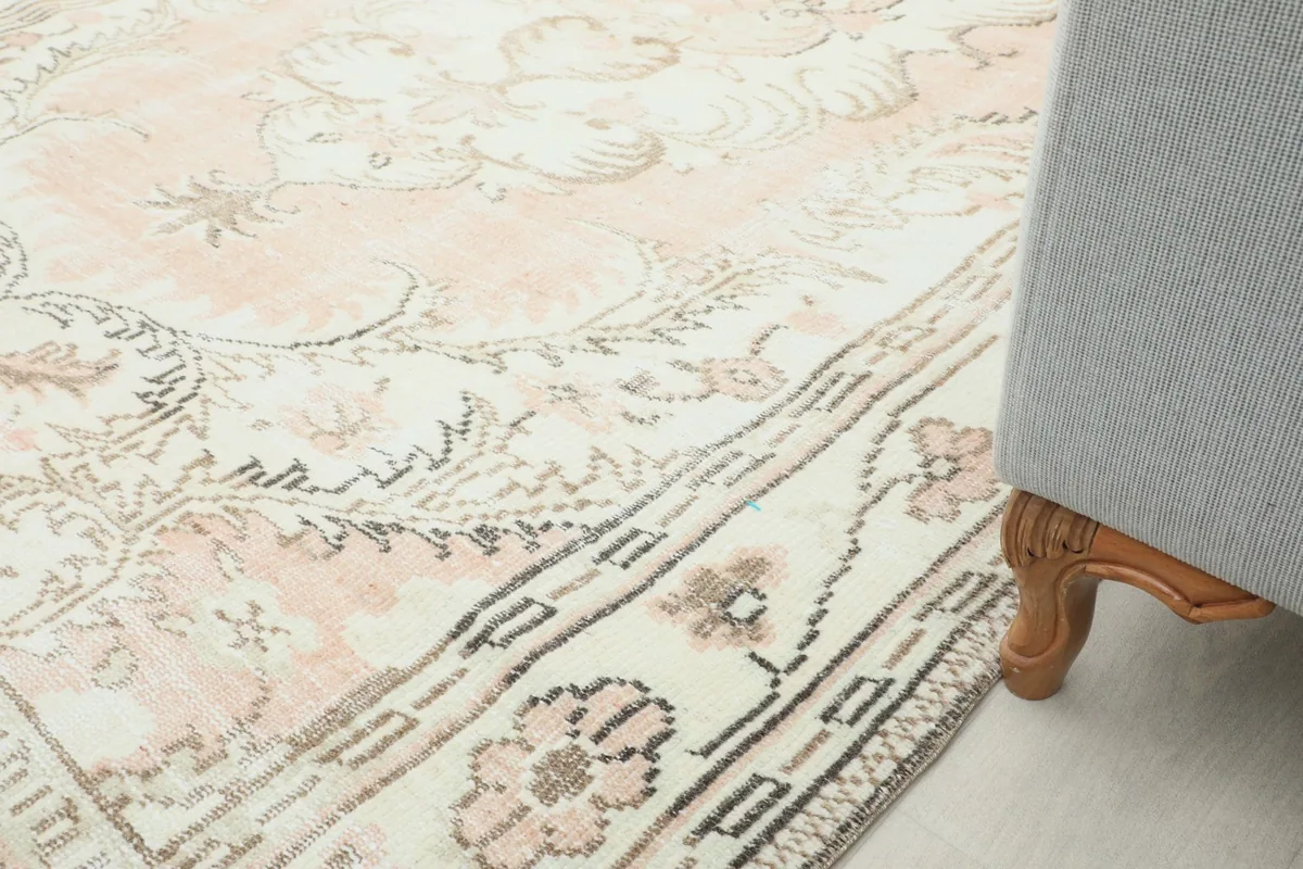 Close-up of the rug's edge and patterns next to a sofa leg, showing color and texture